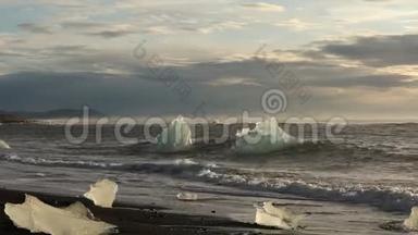 冰山和蓝白冰块在波浪上滚动。 波浪在冰上破碎。 日出时在海滩冲浪。 伊塞拉